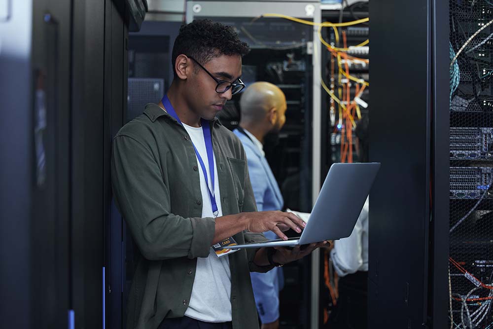 IT work in progress. Cropped shot of two male IT support agents working together in a dark network server room. IT-networking-and-structured-wiring