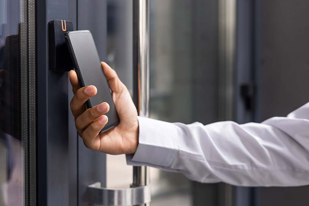 Hand man closely with the phone, the businessman uses the application on the smartphone to remove the door opening of the house, office on premise access control, 1# Toronto Security company, best security company Toronto, experienced security company toronto safelink group, P8MX+GC Brampton, Ontario